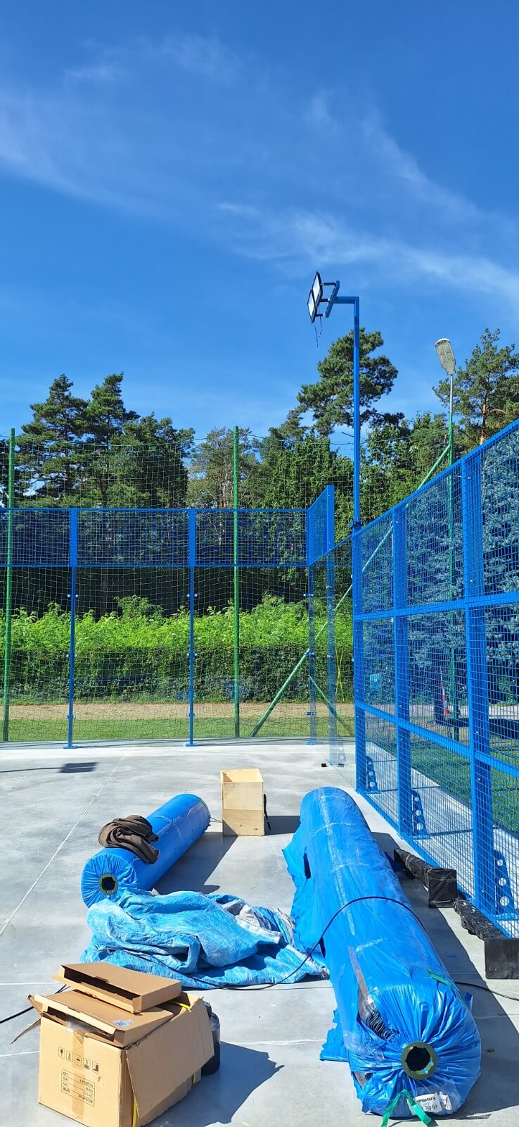 Narożnik kortu do padla i słup oświetleniowy — materiały przygotowane do montażu
